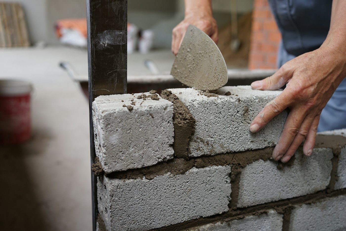 Builder laying concrete blocks with mortar
