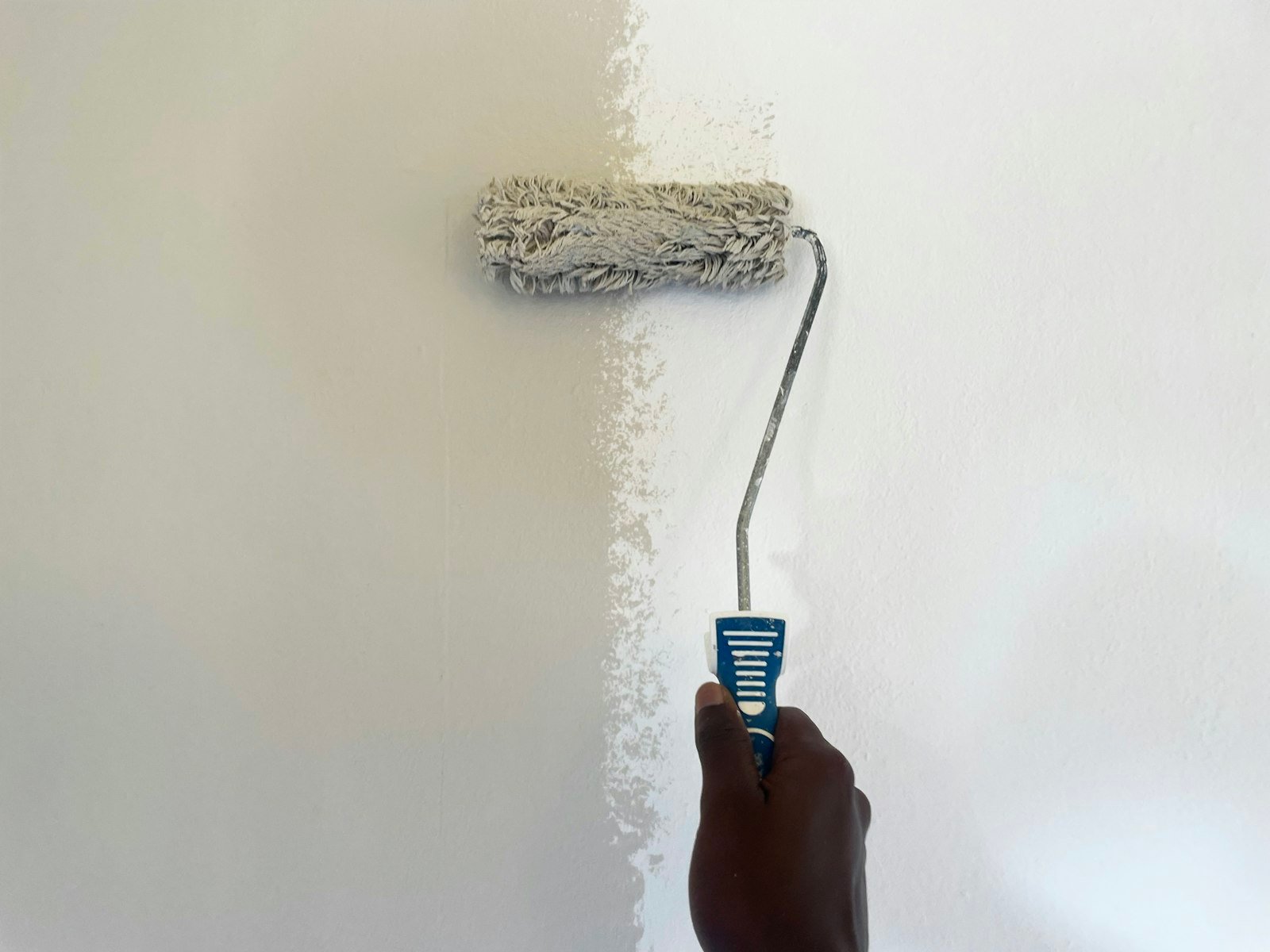 Paint roller applying fresh white paint to an interior wall